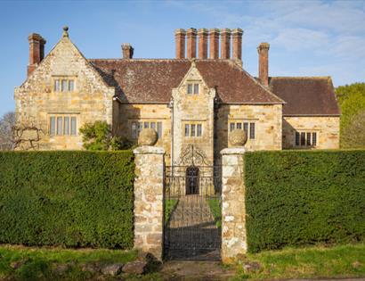 Bateman’s, Rudyard Kipling’s former home, viewed through a wrought-iron gate and clipped hedges.