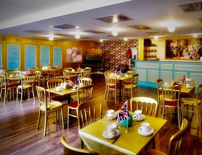 a photograph of the interior the British Tea Museum, Hastings, East Sussex. showing chairs and tables with cups and saucers, with union jack flags as