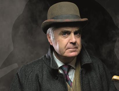 a portrait of a white man in a bowler hat, tie and coat. Background is dark and smokey.