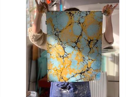marbled paper being held up by hidden person behind.