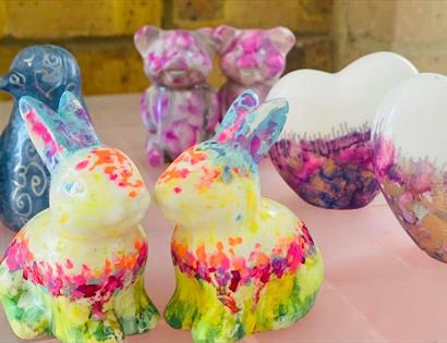 photograph of brightly painted ceramics in the shape of rabbits, penguins, bears and love hearts.