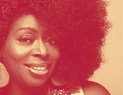 Photograph of lady with large afro, smiling. With an orange filter.