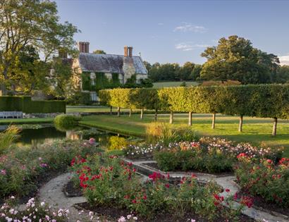formal gardens with stone house in background.