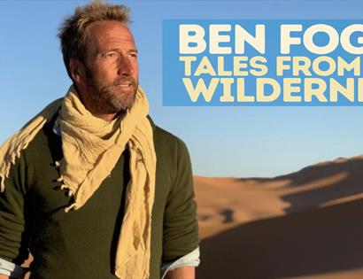 a poster for ben fogle tour at white rock. White man stands in the desert wearing a green top and biege scarf. top right text says ben fogle tales fro