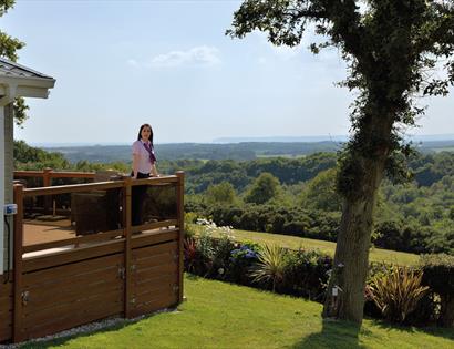 Woman standing on lodge decking enjoying the view  at Crowhurst Park East Sussex