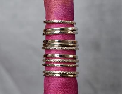 photograph of silver rings stacked together placed through pink linen roll.