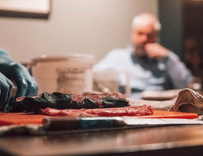 Photograph of a meat being prepared in a pub setting. 