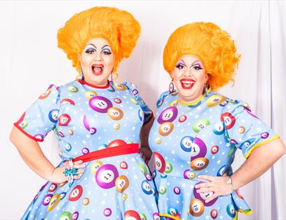 two drag artists wearing colourful dresses