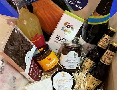 hamper of produce including, glass bottles of fresh fruit juice, beer, wine, gingerbread and jams.