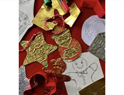 Festive ornament collection on red backdrop, seen from above. Red and gold color palette with round baubles, ribbed and smooth finishes, star shapes, 