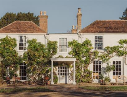 Front view of Crafted at Powdermills with white facade, tiled roof and greenery climbing the walls.