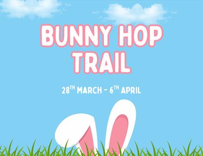 Poster with text ‘Bunny Hop Trail, 28th March–6th April’ above bunny ears poking up from grass against a blue sky.