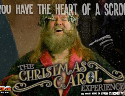 Accessible description: A cheerful holiday character in green robes, red trim, and a holly wreath smiles at the viewer while snow falls. On the right 