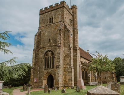 St Mary’s Church, Battle, with medieval stone tower, churchyard monuments and dramatic cloudy skies.