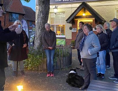 Guided ghost walk group gathered outside the Royal Oak & Castle Inn in Pevensey at dusk with lantern light.
