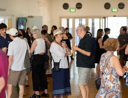 Guests socialise and enjoy refreshments at the Autumn Exhibitions Opening Party in a busy gallery foyer.