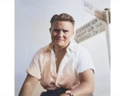 Historic photo from Lemons, Laws & Secret Doors at Hastings Museum, showing a person in a white shirt by a signpost.