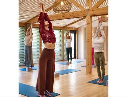 Group yoga session with raised arms in a wooden studio at the Gallivant, Camber during Blue Moonrise class.