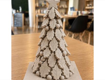 Handcrafted ceramic Christmas tree with layered leaf details and star topper, created in a festive pottery workshop.