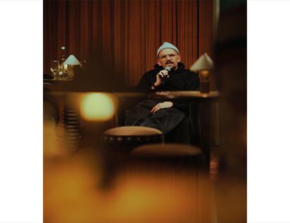 Promotional image for An Evening with Ryan Gander and Holly Walsh, showing a speaker seated on stage with a microphone.