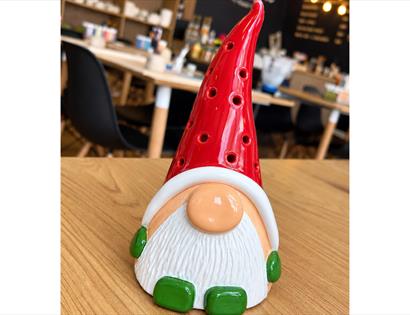 Handcrafted ceramic Christmas gonk with a red hat and white beard, created in a festive pottery workshop.