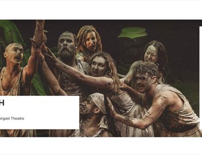 Actors in mud‑covered costumes performing a dramatic group scene from Macbeth, promoted by White Rock Hastings.