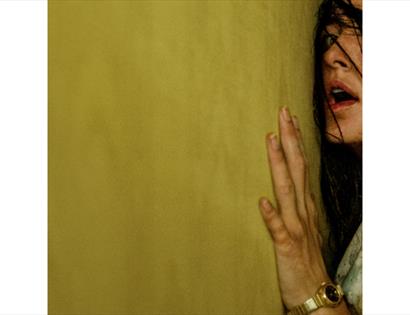 Promotional artwork for Backrooms showing a figure pressed against a yellow wall in a surreal, unsettling setting.