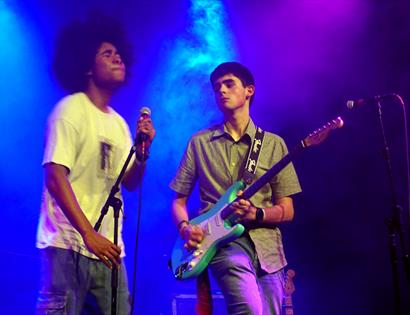 Young musicians performing live on stage at the Create Music Takeover event at the De La Warr Pavilion, under colourful stage lighting.