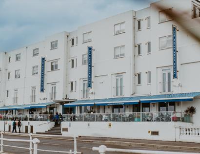 Exterior view of The White Rock Hotel in Hastings with outdoor seating along the seafront promenade.