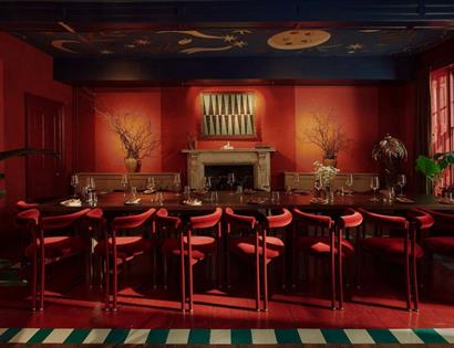 Crafted at Powdermills dining room with rich red interiors, long communal table and a hand-painted celestial ceiling.