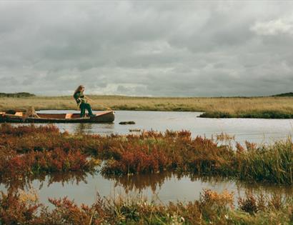 Promotional image for Edge: Where the Land Meets the Sea at Hastings Contemporary, showing a boat on marshland waters.