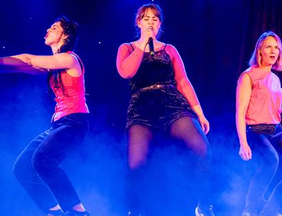 Stage performance by Fannytasticals at the White Rock Theatre, featuring three performers under colourful theatre lighting.
