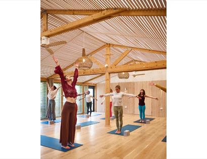 Participants practising yoga on mats in a bright wooden studio during a Harvest Moonrise Yoga session.
