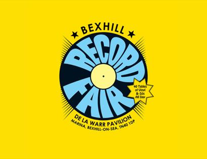 Bright yellow poster for Bexhill Record Fair with vinyl graphic, De La Warr Pavilion, “40 tables of vinyl & DJs all day.”