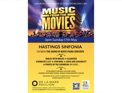 Poster advertising “Music from the Movies” by Hastings Sinfonia at De La Warr Pavilion, featuring a large orchestra on stage.