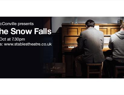Poster for “As the Snow Falls” featuring two performers seated at a piano on stage at Stables Theatre.