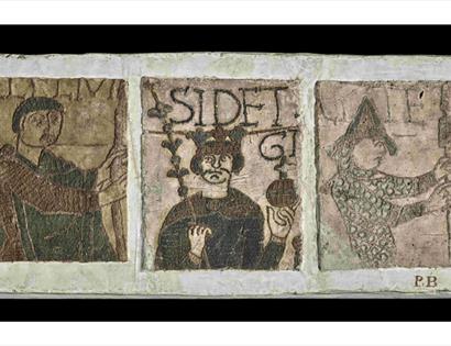 Cast replica panel inspired by the Bayeux Tapestry, showing medieval figures and decorative Norman artwork.