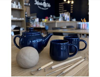 Clay, cuppa and creativity: pottery tools, clay and tea set ready for a relaxed clay-making workshop.