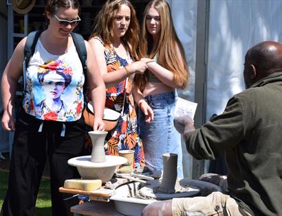 Visitors watch a potter demonstrating wheel throwing at The Sussex Guild Contemporary Craft Show.