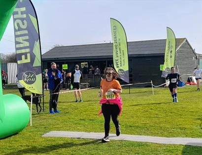 Promotional image for Brett Lydd Half Marathon & 20 Mile, showing runners crossing the finish line outdoors.