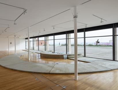 Interior view of De La Warr Pavilion gallery showing Jenine Marsh’s “New Wishes” installation with curved concrete forms and sea views.