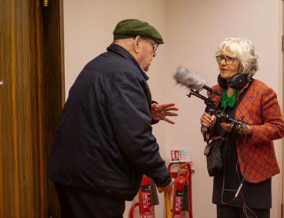 Photo from “90th Birthday Recordings” at De La Warr Pavilion showing an audio recording setup capturing an older participant speaking with a sound rec