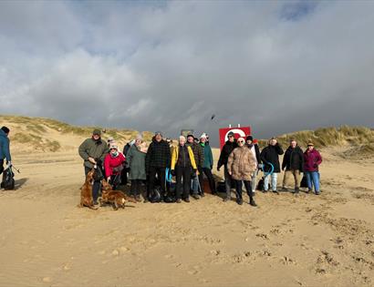 Community group at Camber taking part in The Gallivant’s beach clean, standing on the sand with collected rubbish bags.