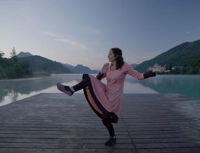 Participant performing a balanced yoga pose on a lakeside dock at the Digestion & Transformation Yoga Masterclass.