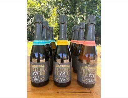 Bottles of Mountfield Winery sparkling wines with coloured labels displayed on a wooden table outdoors.