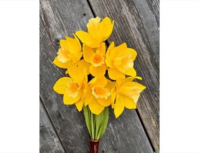 Bright yellow daffodils arranged in a bouquet against a weathered wooden background.