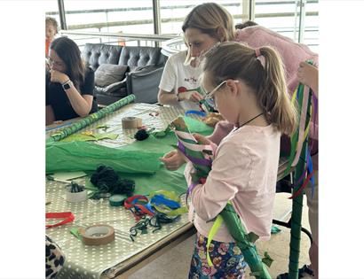Image shows children and parents at a workshop at the De La Warr Pavilion doing arts and crafts.