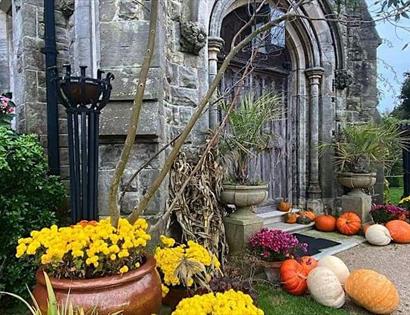 outside porch of an old stone building with flowers and pumpkin display.
