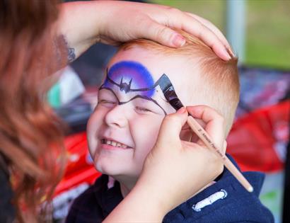 a young boy having his face painted.