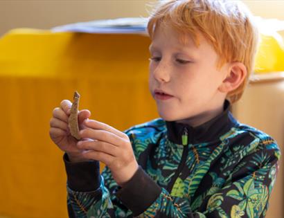 young boy inspecting small archaeological object